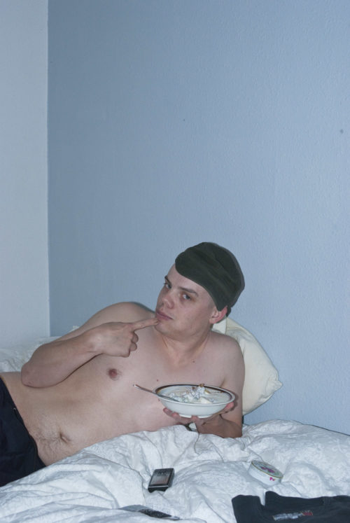 Man liggandes i säng ätande yoghurt